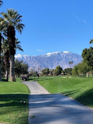 Ein Golfplatz mit einer deutlichen Wegeführung, im Hintergrund ein Gebirgszug.