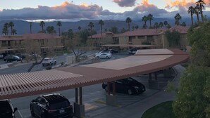A hotel with a parking area, a covered walkway, and a view of mountains and clouds. - Coachella @ Marriott’s Palm Desert Villas II, One bedroom/Kitchen on golf course (Palm Desert)