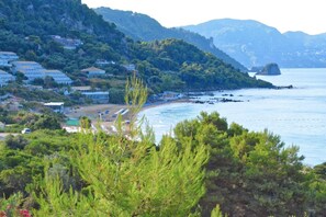 Eine Küstenstadt mit Häusern entlang des Strandes, einer felsigen Küstenlinie und üppigem Grün im Vordergrund.