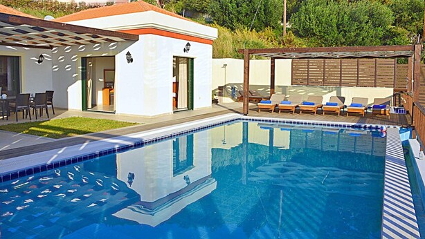 Uma piscina com espreguiçadeiras e um pérgola.