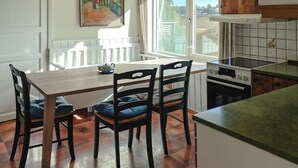 Une cuisine équipée d’une table et de chaises, d’une cuisinière, et offrant une vue sur l’extérieur.