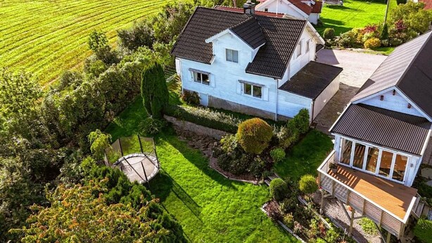 Une maison à deux étages avec une pelouse bien entretenue, une allée circulaire et un petit jardin.