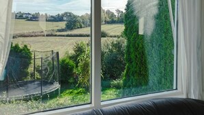 Une pièce dotée d’une grande fenêtre donnant sur un trampoline et un champ d’herbe.