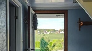 Un couloir menant à une porte donnant sur un jardin et des maisons.