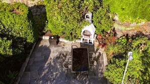 Une terrasse avec un sol en pierre, un barbecue et des meubles d’extérieur.