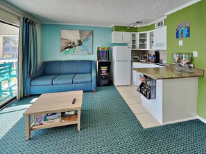 Ein gemütlicher Wohnraum mit Sofa, Couchtisch, Küchenzeile und einem Bild an der Wand.