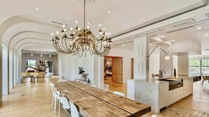 Eine geräumige Küche mit einer großen Kochinsel, einem Holzessttisch und einer prächtigen Kristallleuchter.