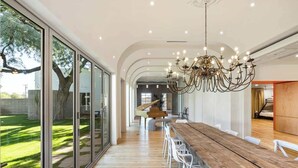 Ein moderner Essbereich mit einem langen Holztisch, weißen Stühlen und einer Chandelüster.