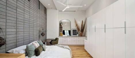 Ein modernes Schlafzimmer mit Bett, Holzboden, einem weißen Kleiderschrank und einem Schreibtisch mit Stuhl.