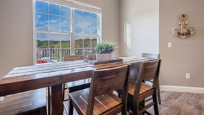 A dining area with a large window, wooden table, and chairs.