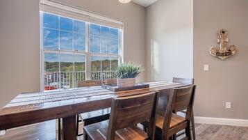 A dining area with a large window, wooden table, and chairs.