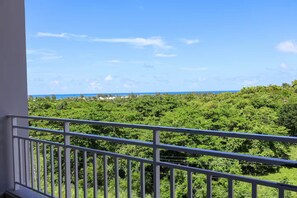 A balcony with a view of dense greenery and a distant coastline. - Penthouse with Pool Near El Yunque & Luquillo Beaches (Río Grande)