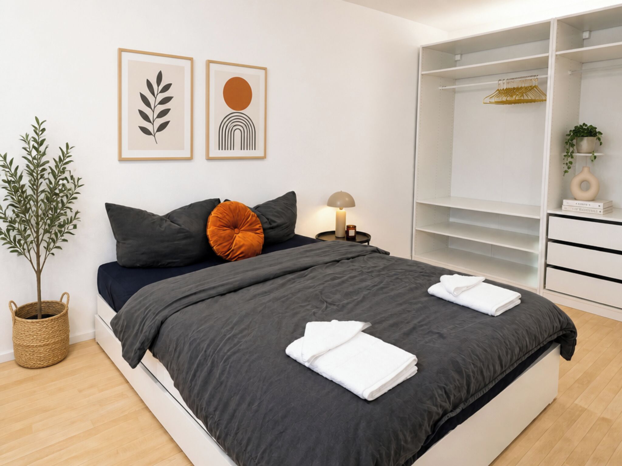 A modern bedroom with a bed, bedside table, lamp, and a wardrobe.