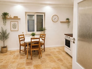 A kitchen with a dining table, chairs, a clock, and a stove. - 1OG R City Wohnung Balkon nähe Salzburg (Freilassing)