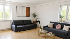 A modern living room with two sofas, a coffee table, and a painting on the wall. - 1OG R City Wohnung Balkon nähe Salzburg (Freilassing)