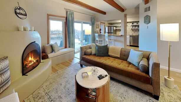 A cozy living room with a fireplace, a sofa, a coffee table, and a view of the city through large windows. - Casa Cielo (Santa Fe)