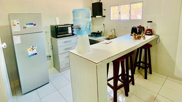 Une cuisine équipée d’un réfrigérateur, d’un distributeur d’eau, d’un four à micro-ondes, d’une cuisinière et d’un coin bar avec des tabourets.