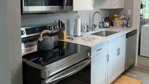 Een moderne keuken met roestvrijstalen apparatuur, witte keukenkastjes en een inbouwoven.