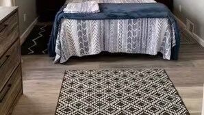 Een slaapkamer met een bed, twee nachtkastjes, een plafondventilator en een vloerkleed.