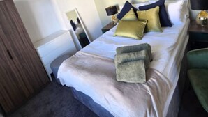 A neatly arranged bedroom with a bed, bedside tables, a mirror, and a wardrobe. - West Midlands Home - 3BR w/FREE Parking and WIFI (West Midlands)