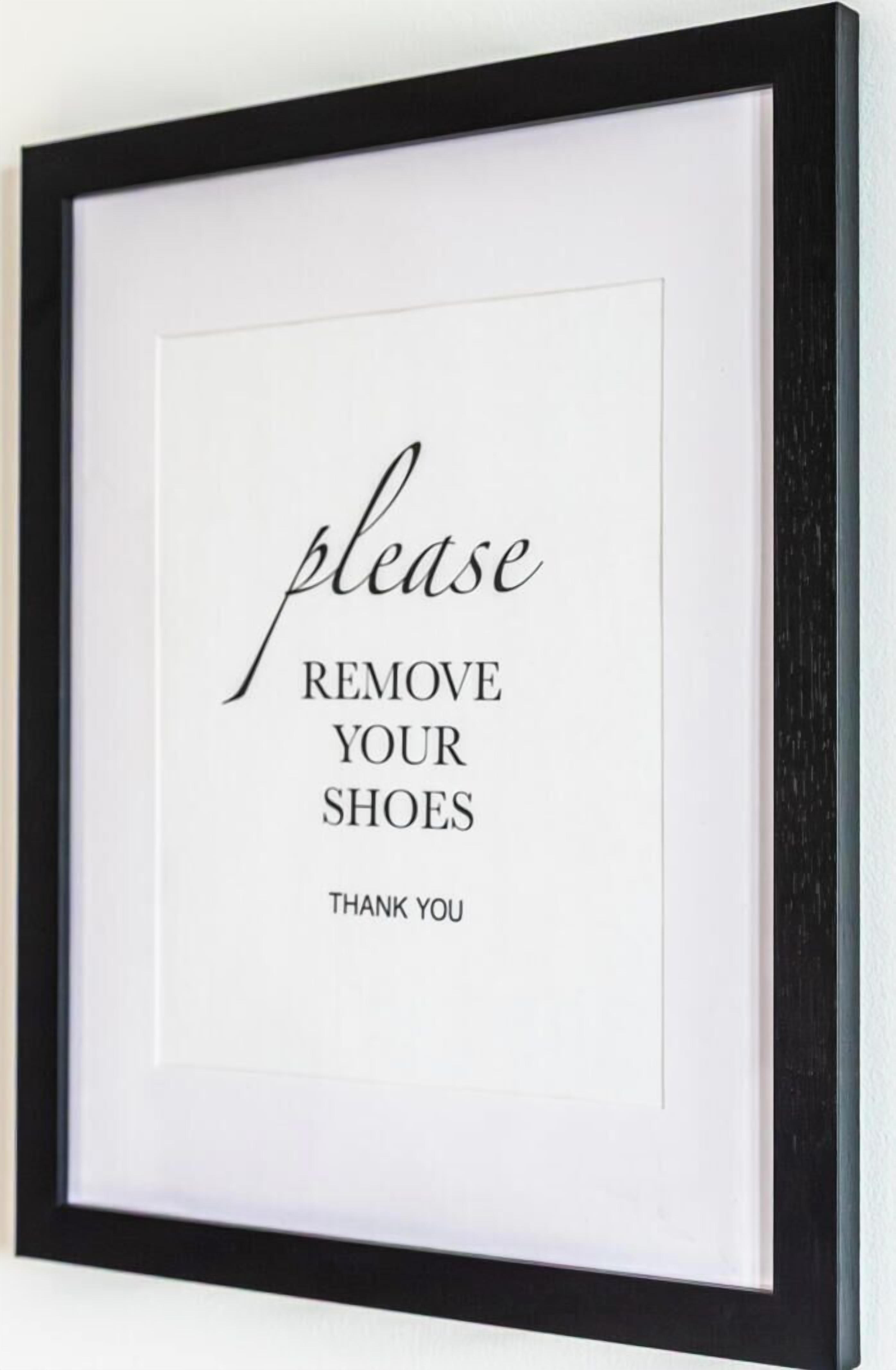 A framed sign with the text "please REMOVE YOUR SHOES Thank you".