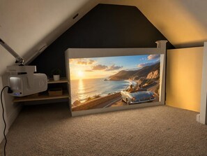 A room with a projector on a shelf, a large scenic wall, and a carpeted floor. - 3BR Thames Retreat | Heathrow 10min | Train 5min (Egham)