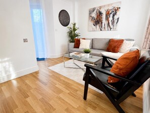 A modern living room with a sofa, coffee table, and a black chair. - 3BR Thames Retreat | Heathrow 10min | Train 5min (Egham)