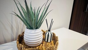 Un tavolo bianco con un cesto intrecciato che contiene una pianta in vaso e un portacandela a righe.
