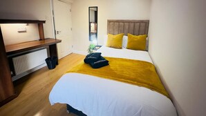 Una camera d'albergo con un letto, una scrivania, uno specchio e un termosifone.