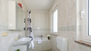 Ein modernes Badezimmer mit Waschbecken, Toilette, Badewanne und Duschvorhang.