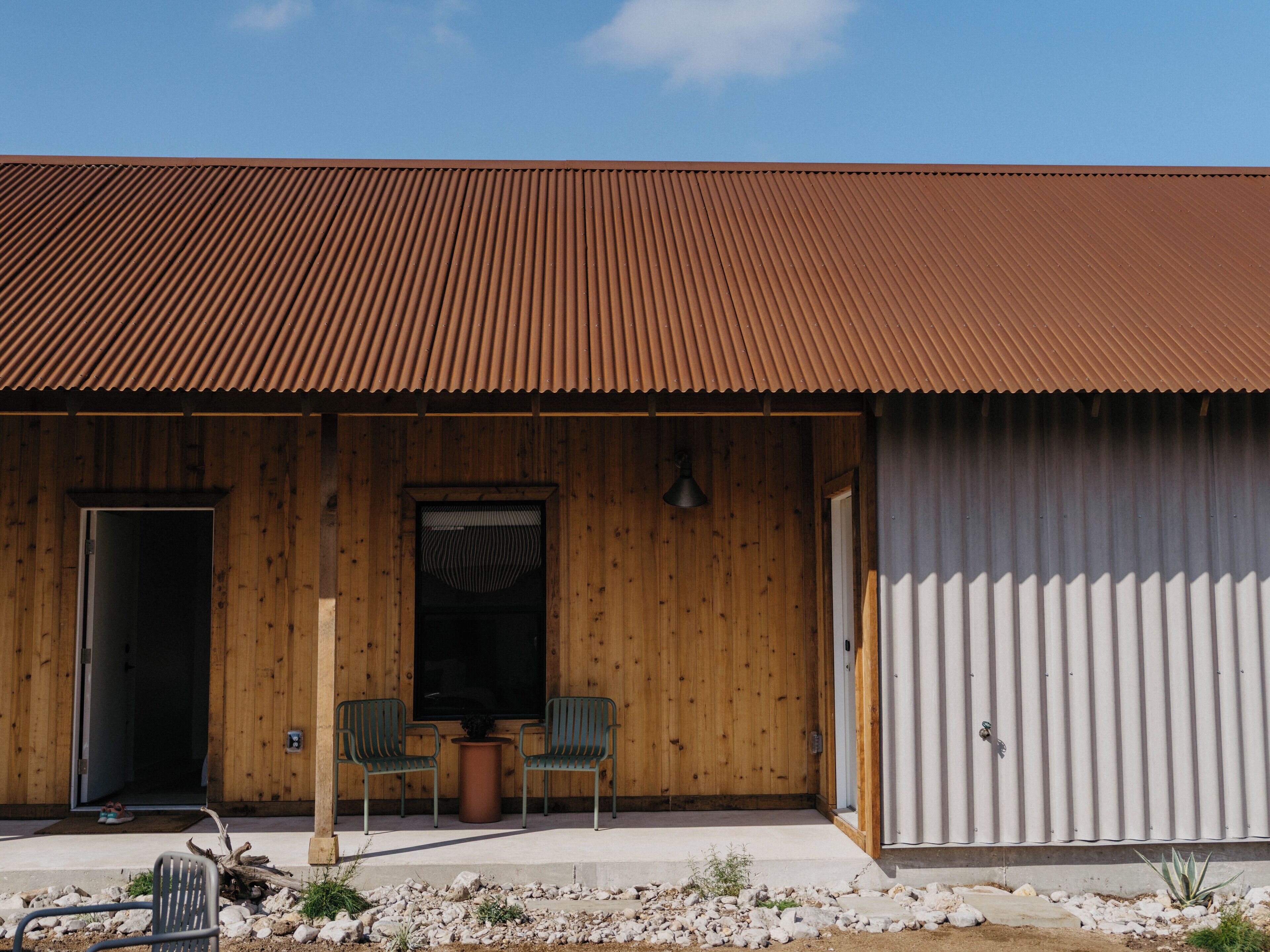 A building with a wooden facade, a corrugated metal roof, and a large garage door.