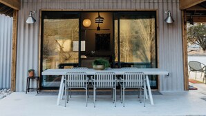A modern house with a large porch, a dining table, and two chairs.