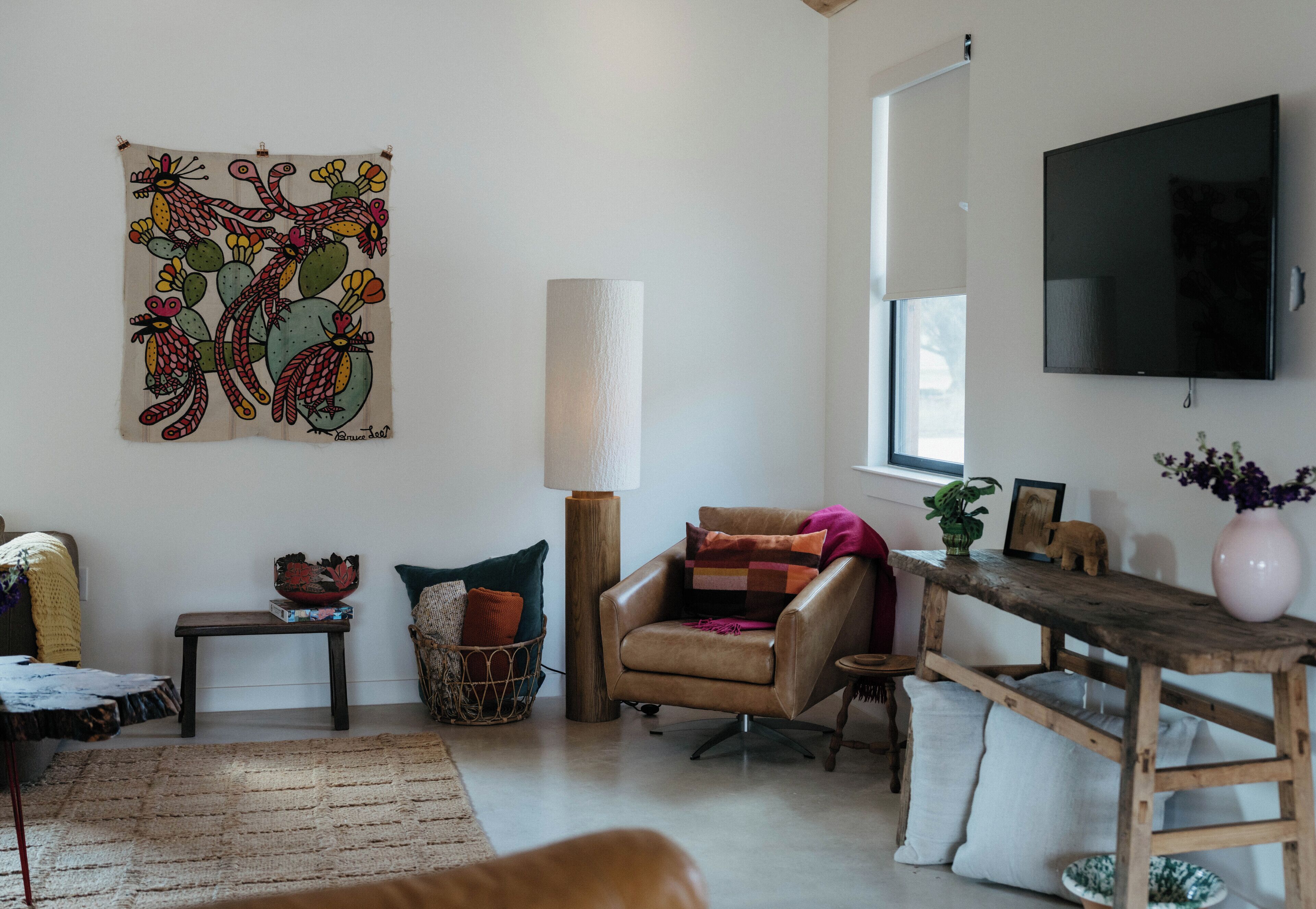 A living room with a sofa, armchair, coffee table, and a wall-mounted TV.