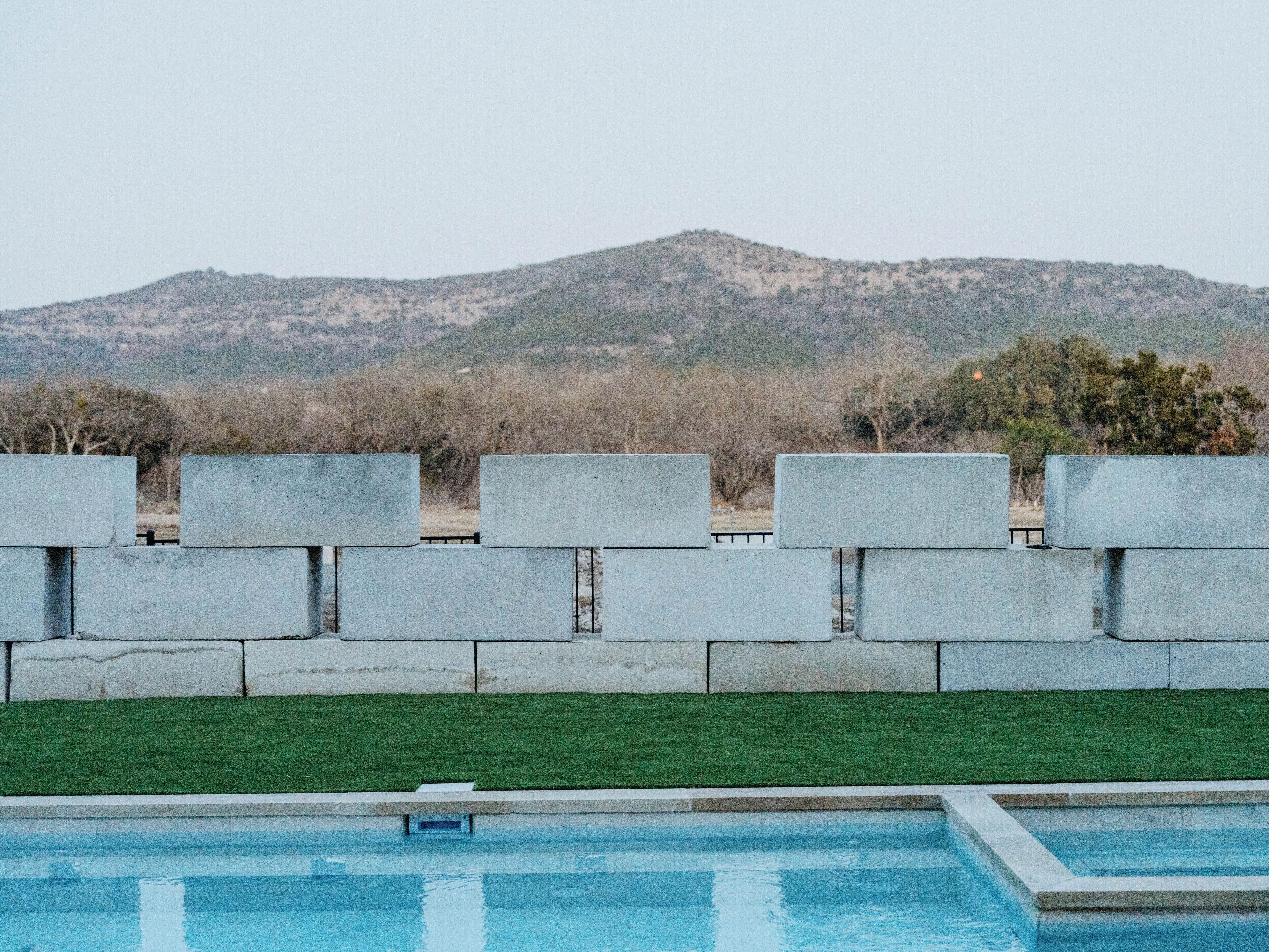 A swimming pool with a view of a hilly landscape and a concrete barrier.