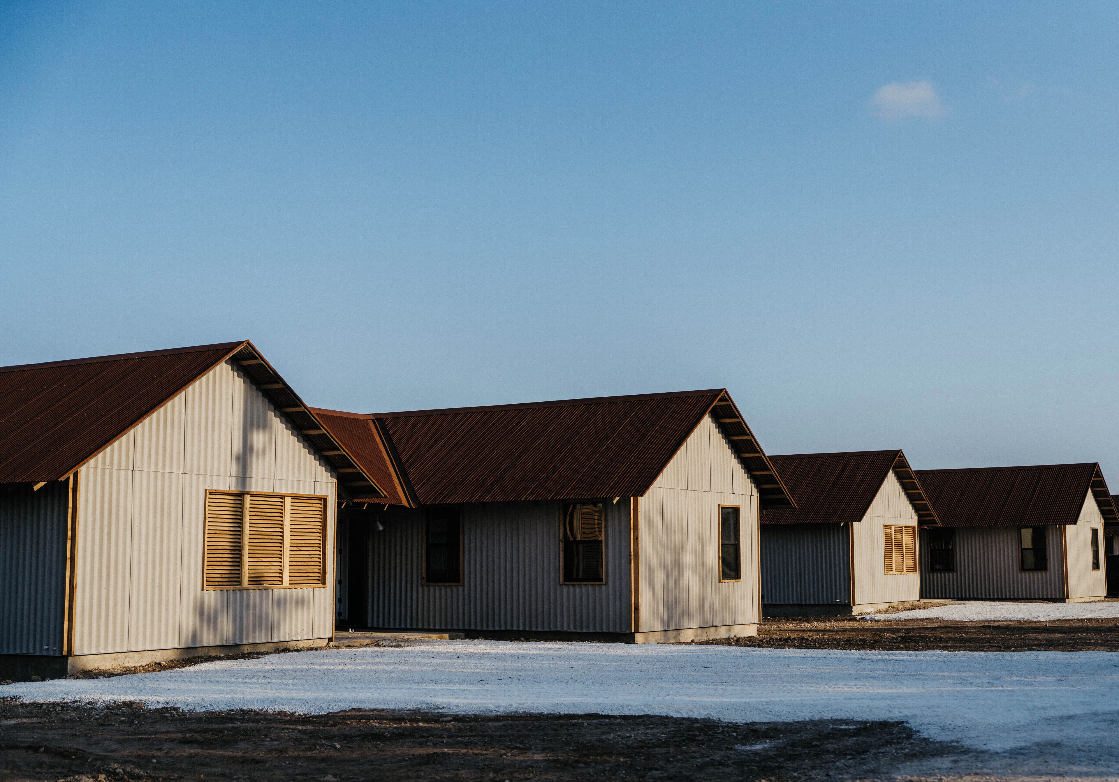 A row of small, single-story buildings with sloped roofs and wooden shutters, likely used for storage or as utility buildings.