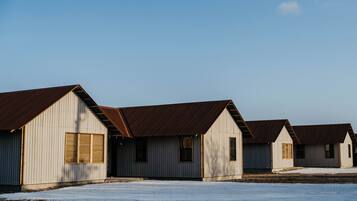 A row of small, single-story buildings with sloped roofs and wooden shutters, likely used for storage or as utility buildings.