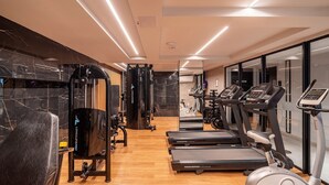 Un gimnasio moderno con cintas de correr, elípticas y equipo de levantamiento de pesas.
