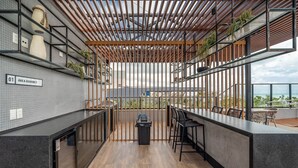 Cocina moderna con techo de madera, un letrero que dice 'Area Gourmet' y vista al océano.