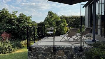 A patio area with a stone wall, outdoor furniture, and a large umbrella.