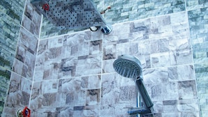 Douchegedeelte met een regendouche en een handdouche voor een betegelde muur.