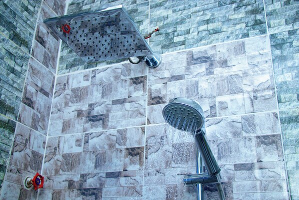 Douchegedeelte met een regendouche en een handdouche voor een betegelde muur.
