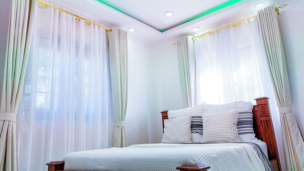 Un dormitorio con cama, cortinas y lámpara en el techo.