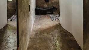 Una stanza con una panca in cemento, un portasciugamani e un lampadario.