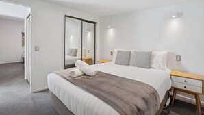Una camera d'albergo moderna con un grande letto, un comodino e uno specchio.