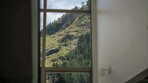Vista dalla finestra su un paesaggio montuoso con una seggiovia, che suggerisce una località vicino a una stazione sciistica.