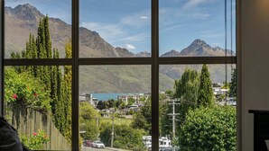 A view through a window with a mountain landscape, including a lake and buildings. - Peaks & Cranbury 17B:  Location & Views ! (Queenstown)