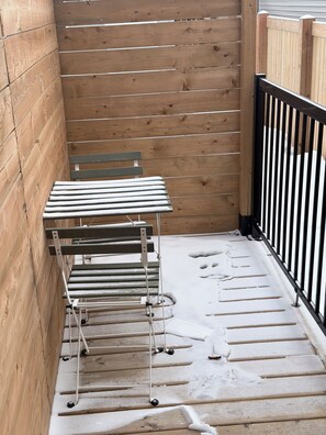 Eine Holzterrasse mit einer Metallbank und einem Metallgestell.