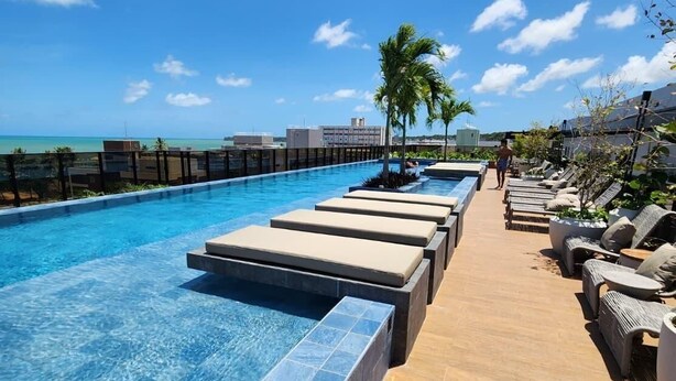 Une piscine avec des chaises longues et vue sur l’océan.