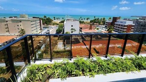 Un balcon offrant une vue sur un paysage urbain côtier, avec des bâtiments et une plage.
