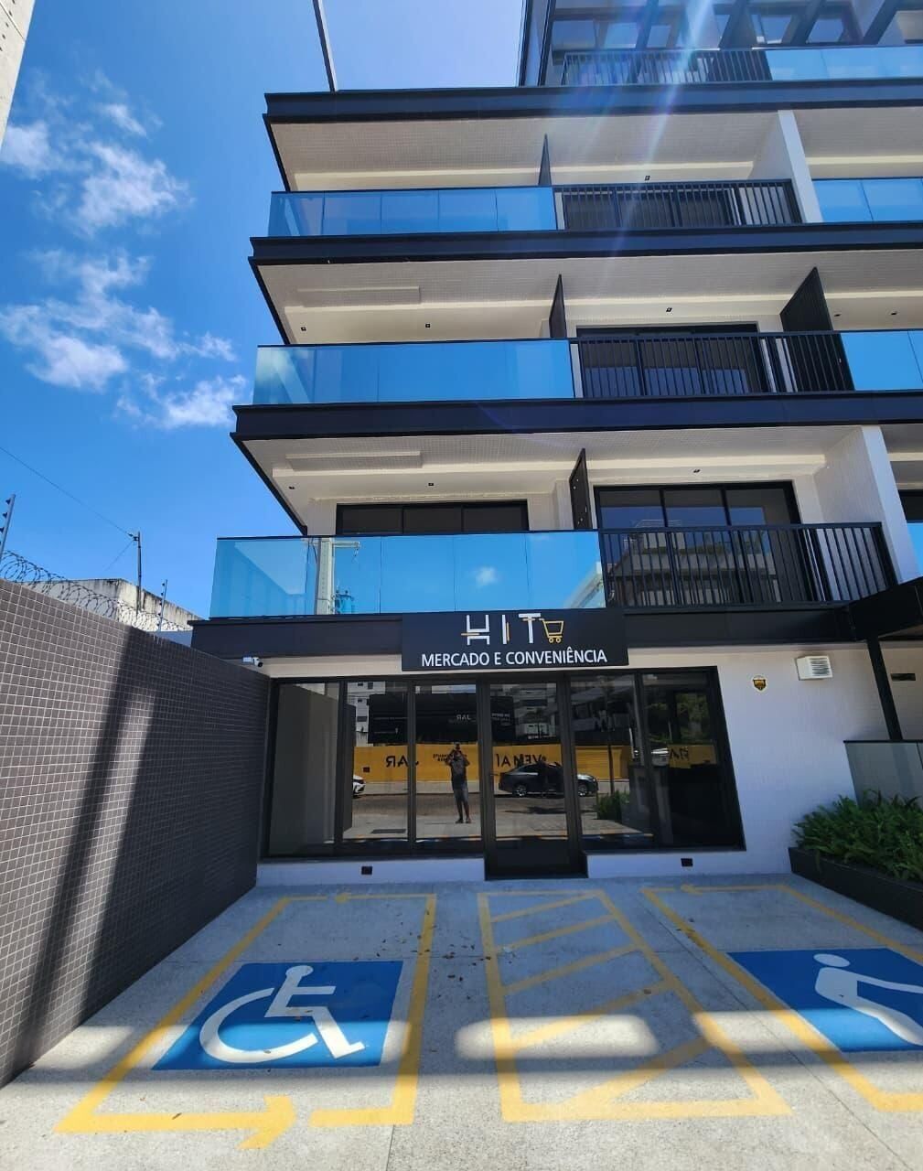 Um edifício de vários andares com uma fachada que exibe a placa 'HIT Mercado e Conveniência'.